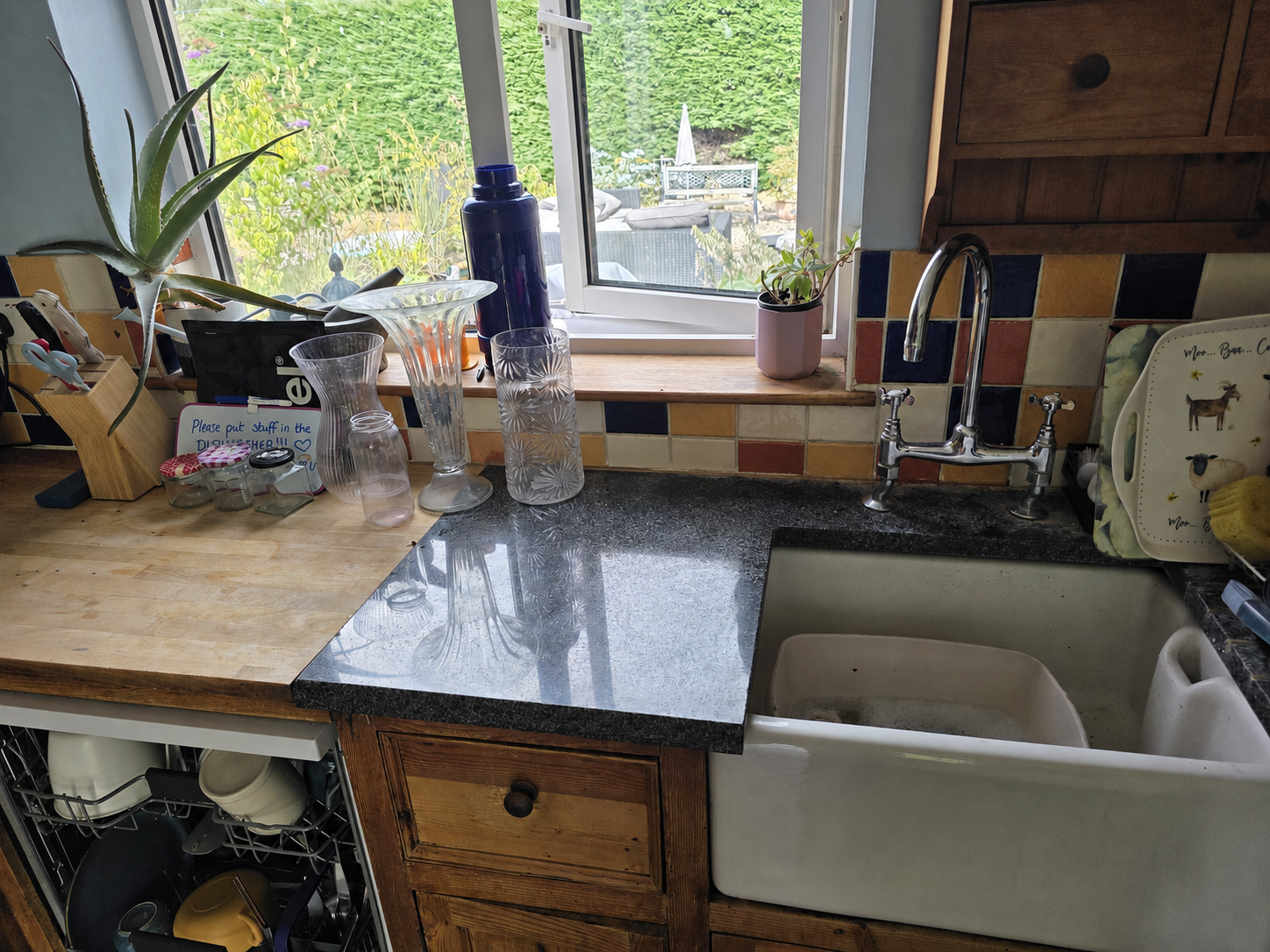 A real, cluttered kitchen sink area before clearing, cleaning and styling